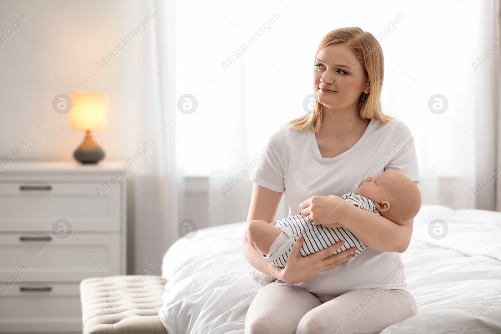 Photo of Young mother with her baby on bed at home