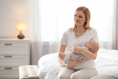 Young mother with her baby on bed at home