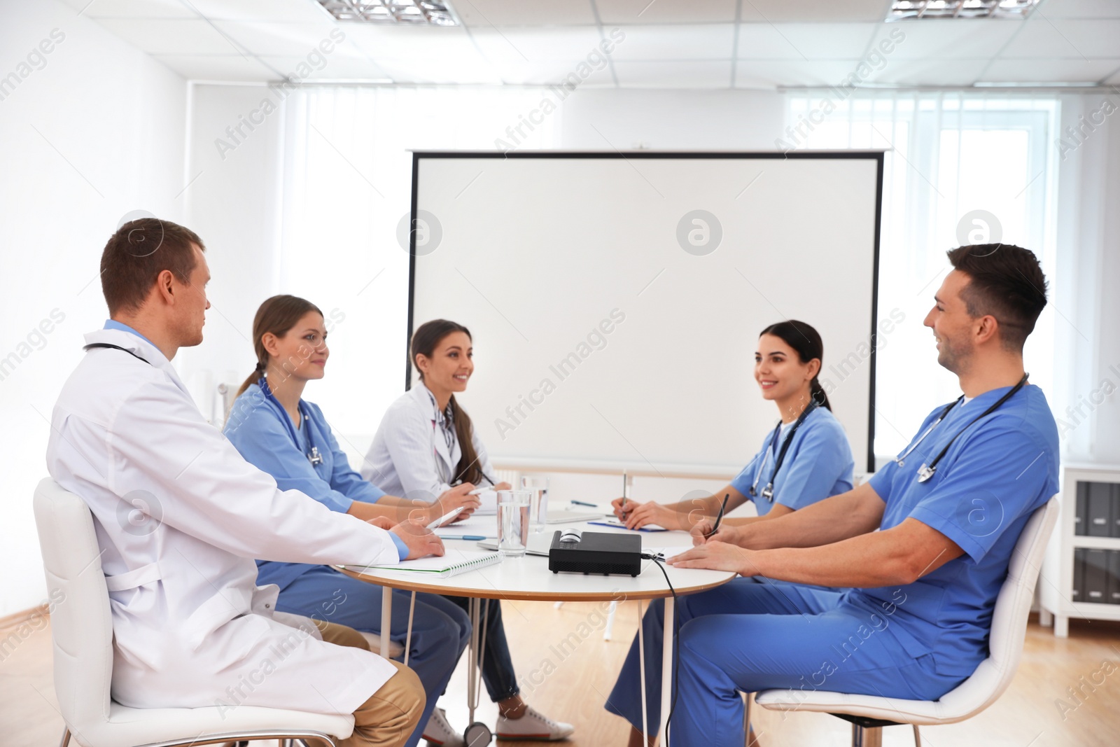 Photo of Team of doctors using video projector during conference indoors