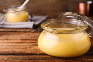 Photo of Glass jar of Ghee butter on wooden table, closeup. Space for text