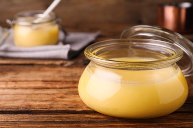 Glass jar of Ghee butter on wooden table, closeup. Space for text