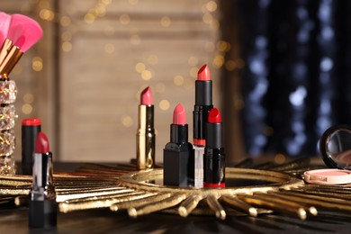 Photo of Beautiful red and pink lipsticks on table against blurred lights