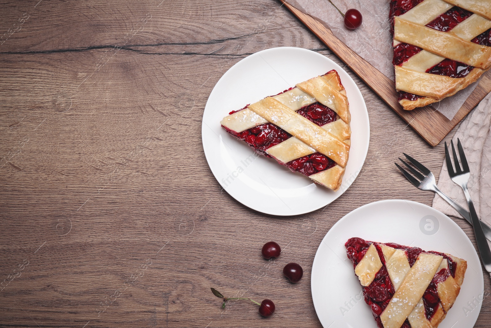 Photo of Slices of delicious fresh cherry pie served on wooden table, flat lay. Space for text