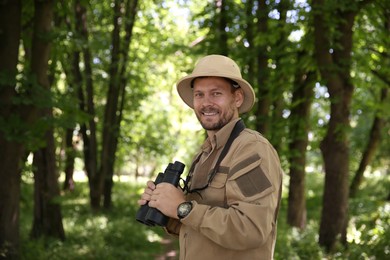 Forester with binoculars examining plants in forest