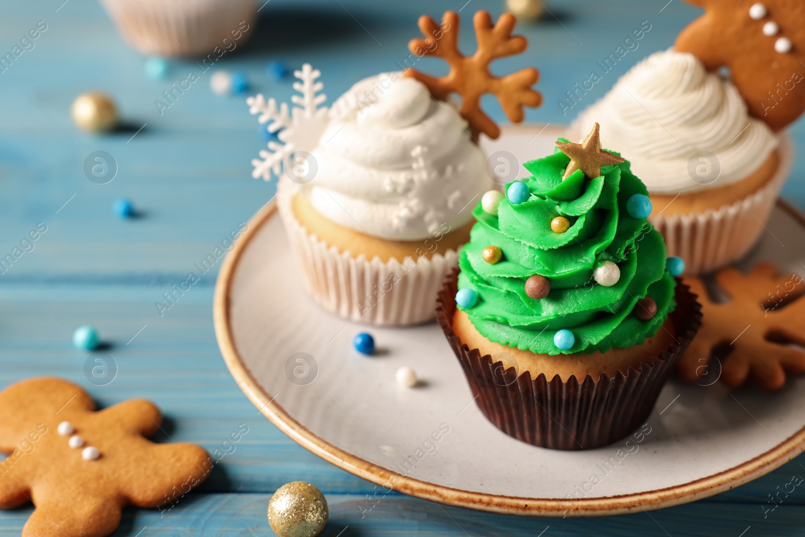 Photo of Different beautiful Christmas cupcakes on light blue wooden table