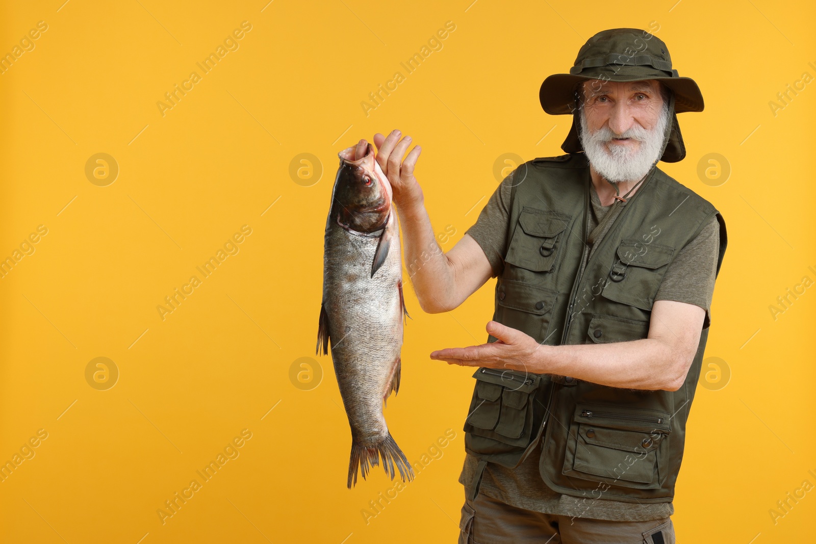 Photo of Fisherman with caught fish on yellow background, space for text