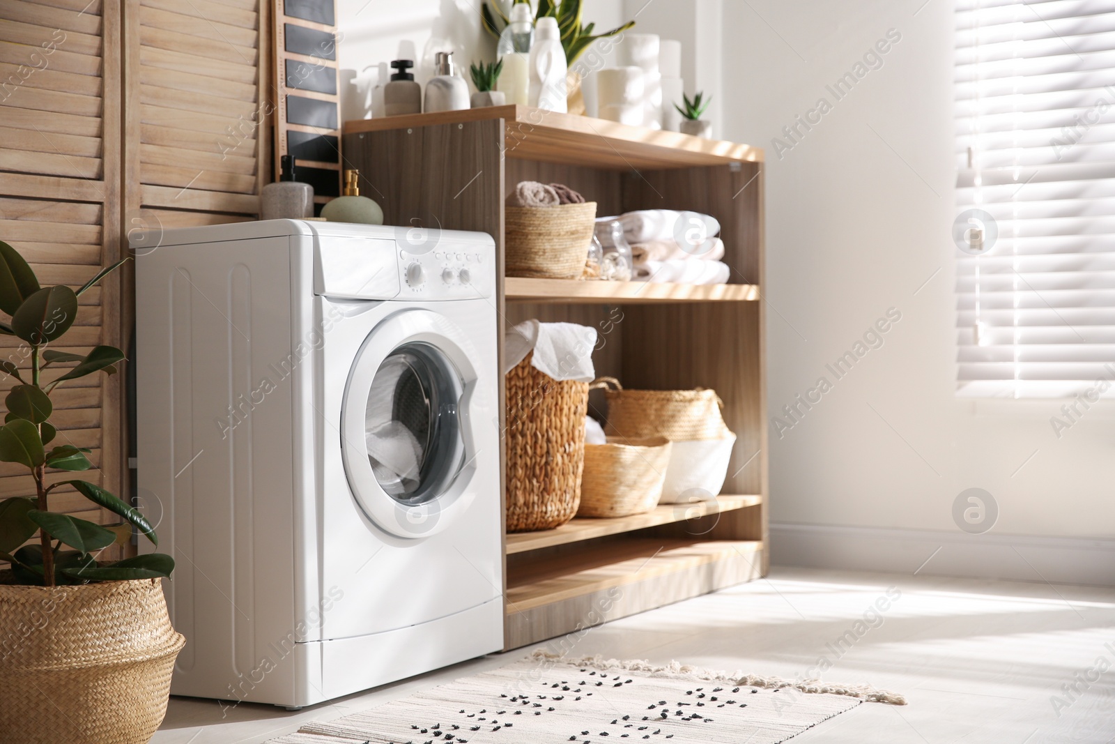 Photo of Modern washing machine and shelving unit in laundry room interior