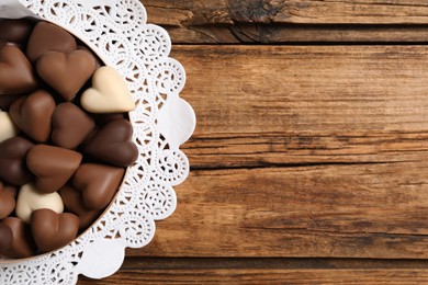 Delicious heart shaped chocolate candies on wooden table, top view. Space for text