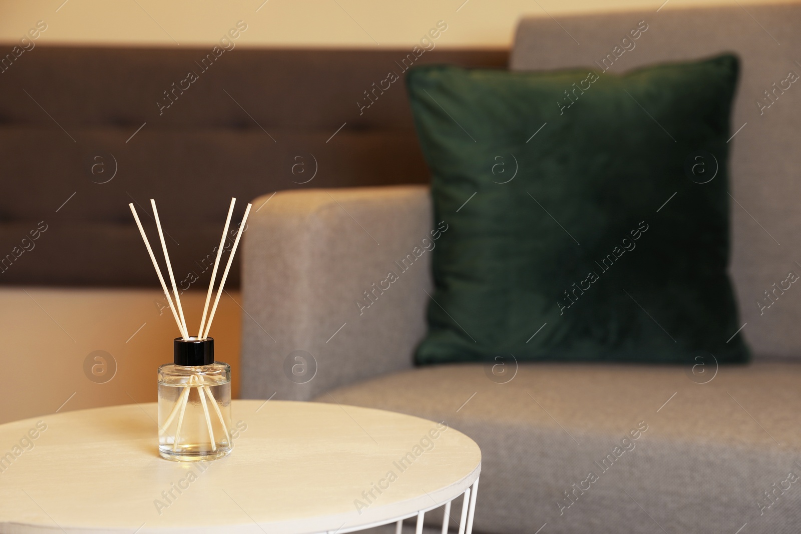 Photo of Aromatic reed air freshener on wooden table indoors, space for text