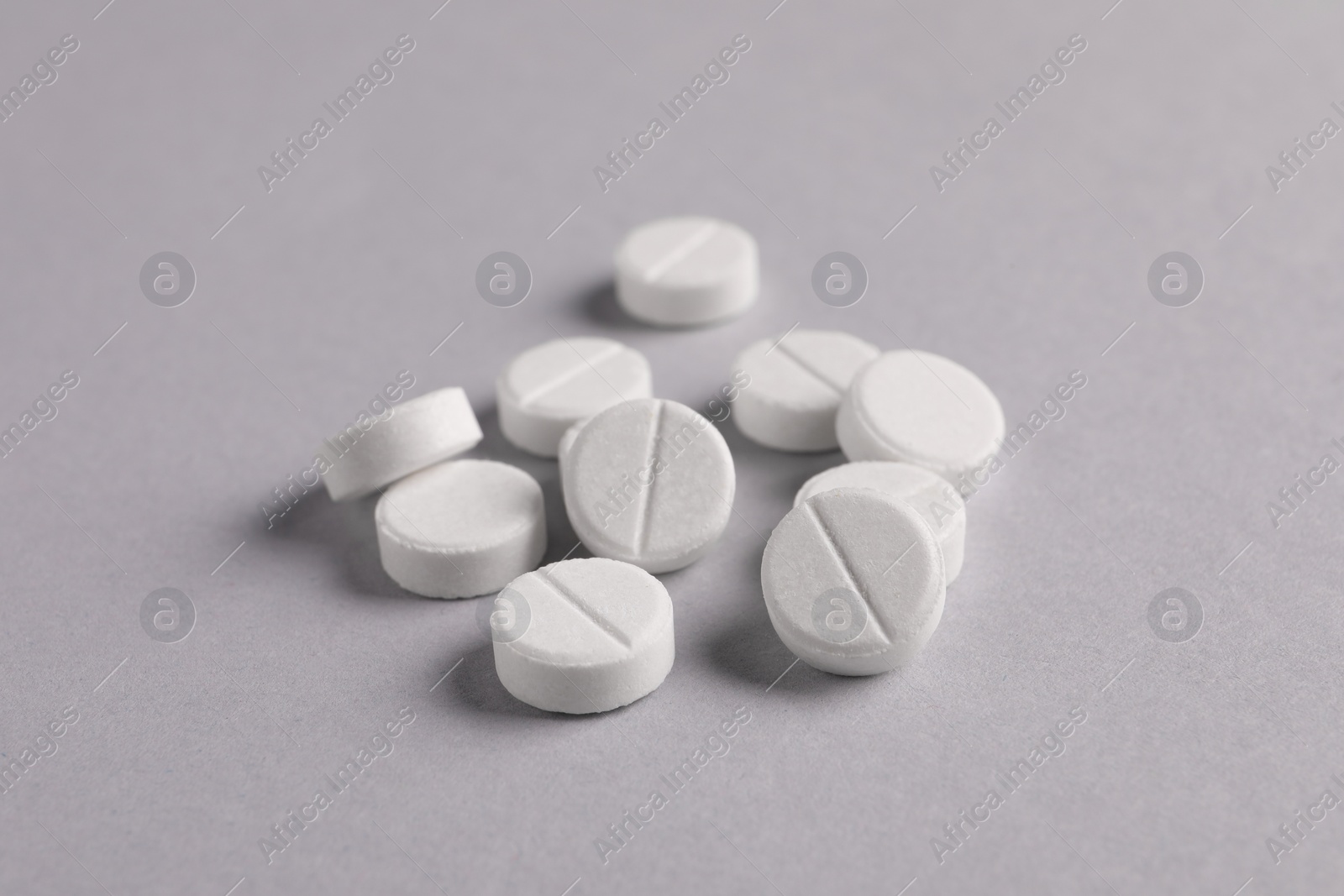 Photo of Pile of round pills on light grey background