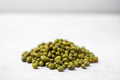 Photo of Pile of green mung beans on light grey table, closeup