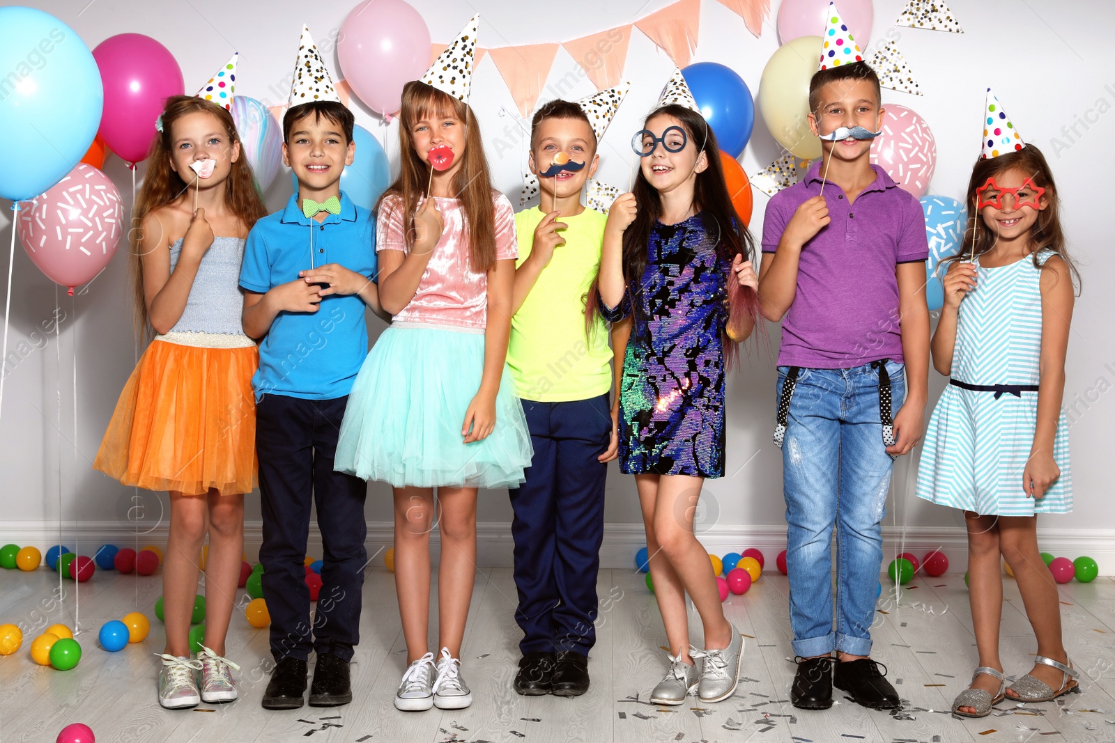 Photo of Happy children with photo booth props at birthday party indoors