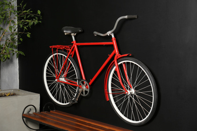Photo of Red bicycle hanging on black wall indoors