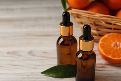 Bottles of tangerine essential oil on white wooden table, space for text