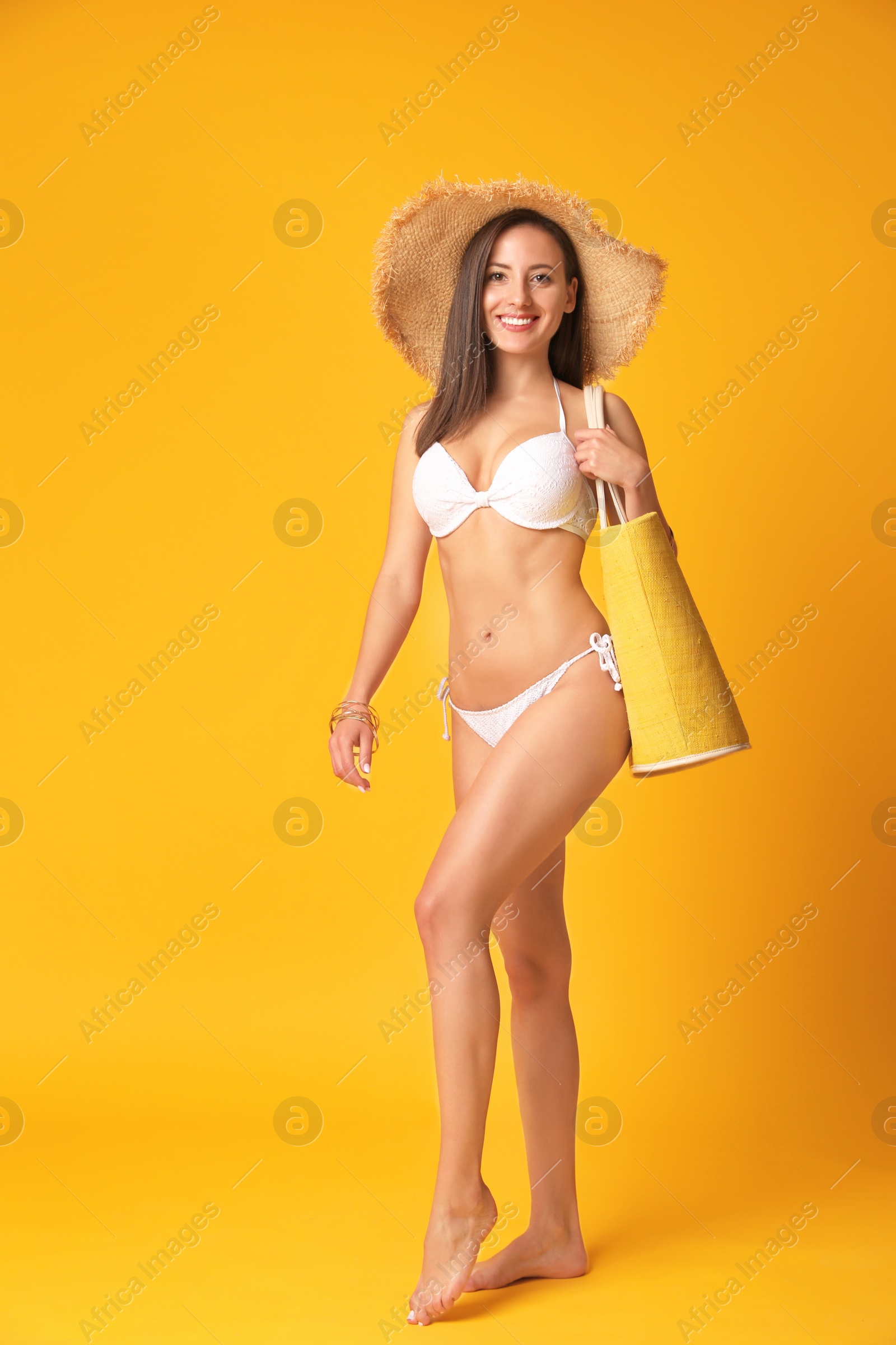 Photo of Pretty sexy woman with slim body in stylish white bikini on orange background