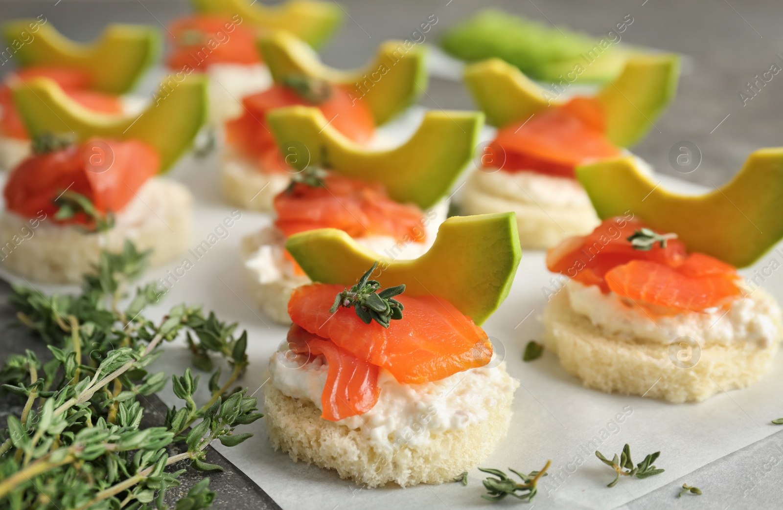 Photo of Tasty sandwiches with fresh sliced salmon fillet and avocado on table, closeup