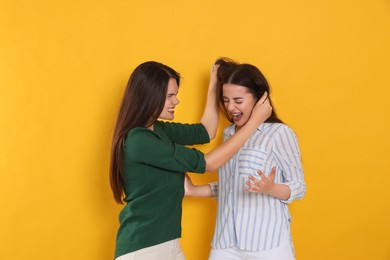 Photo of Aggressive young women fighting on orange background