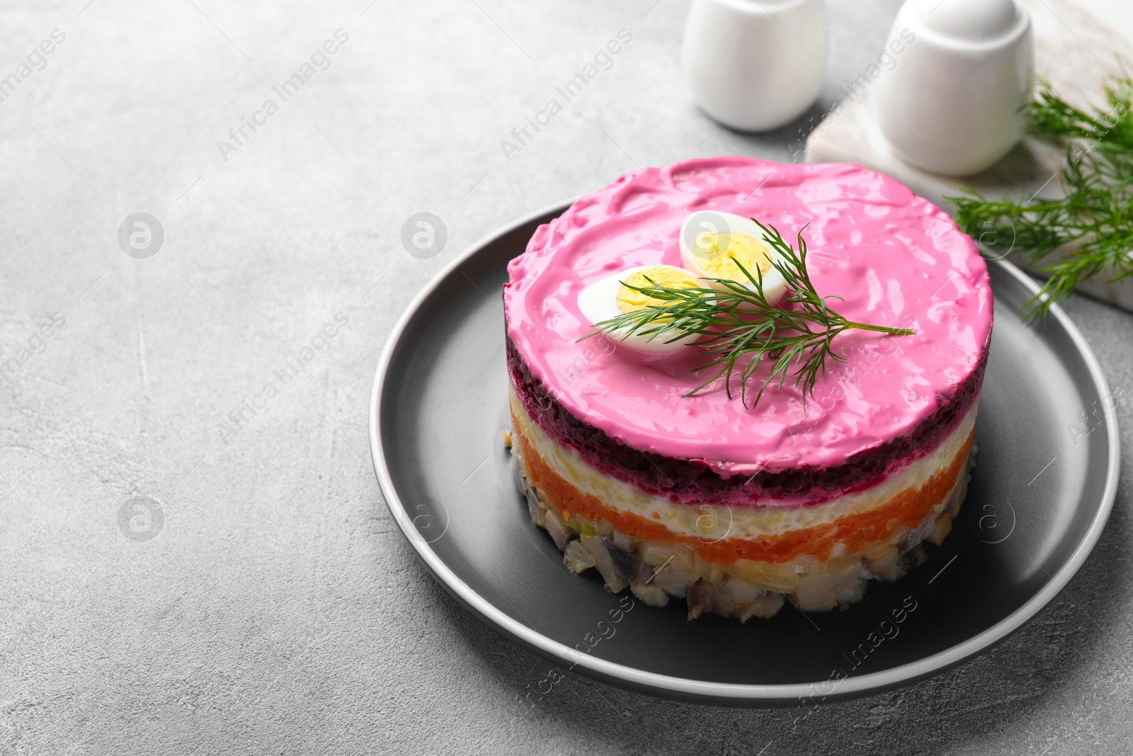 Photo of Herring under fur coat salad on light grey table, space for text. Traditional Russian dish