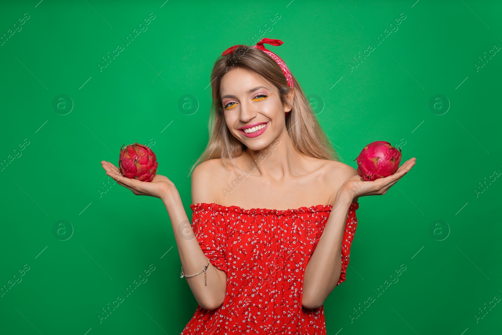 Photo of Young woman with fresh pitahayas on green background. Exotic fruits