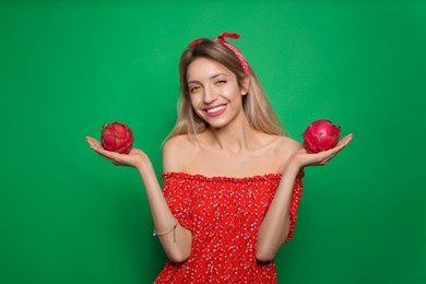 Photo of Young woman with fresh pitahayas on green background. Exotic fruits