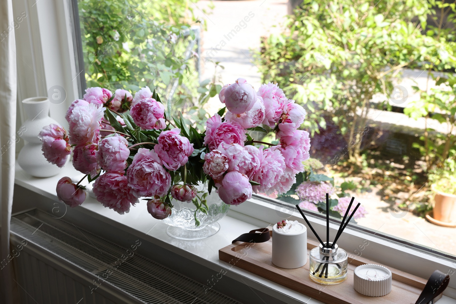 Photo of Beautiful pink peonies in vase on window sill. Interior design