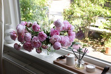 Photo of Beautiful pink peonies in vase on window sill. Interior design