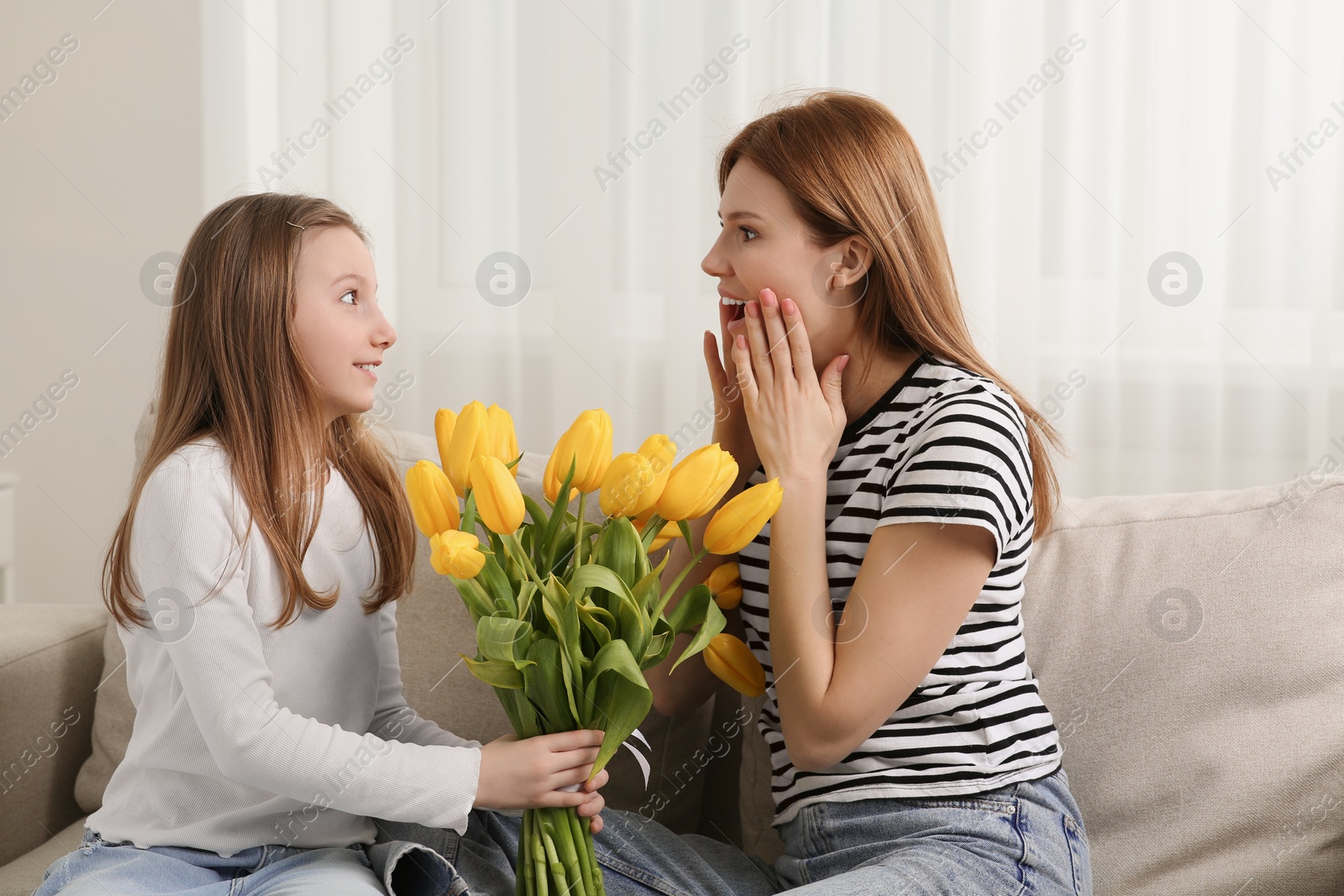 Photo of Daughter congratulating mom with bouquet of yellow tulips at home