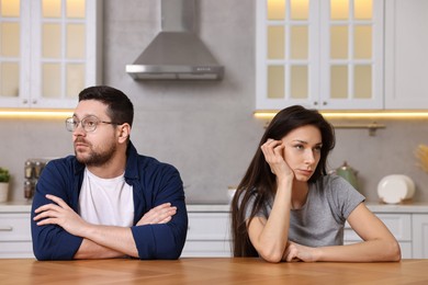 Offended couple ignoring each other after quarrel at table in kitchen. Relationship problems