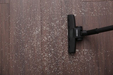 Photo of Vacuuming scattered rice from wooden floor, top view. Space for text