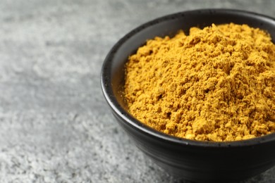 Dry curry powder in bowl on dark textured table, closeup. Space for text