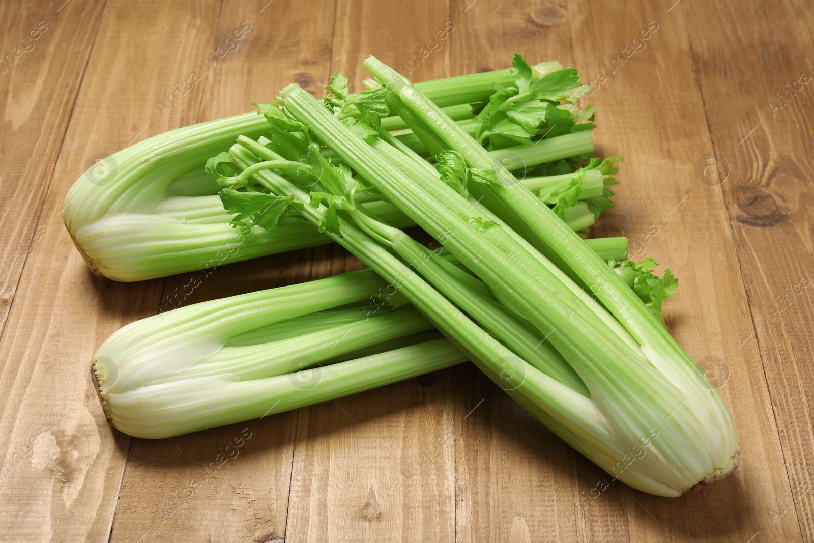Photo of Bunches of fresh green celery on wooden table