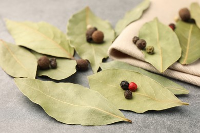 Aromatic bay leaves and spices on light gray table, closeup