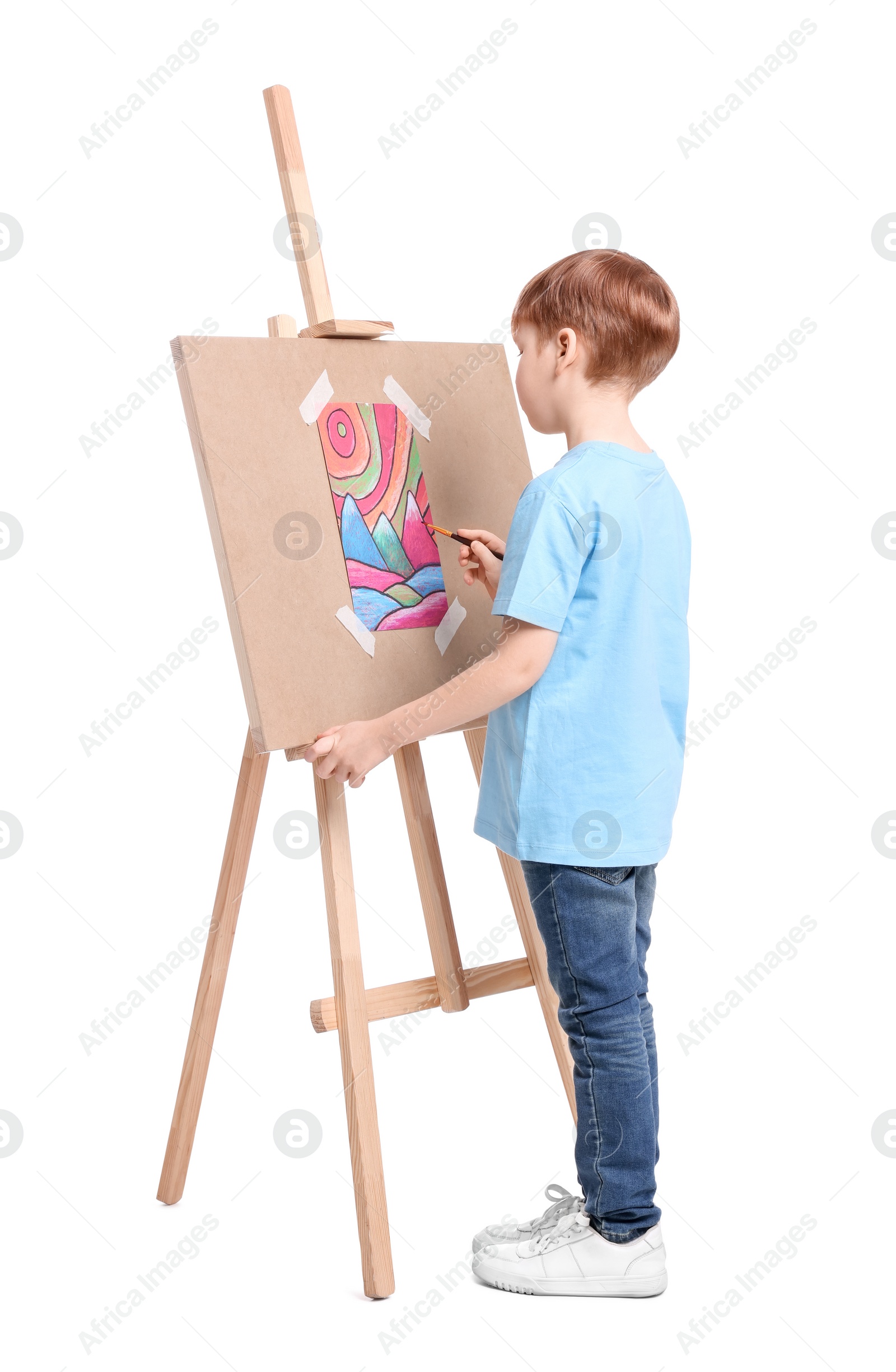 Photo of Little boy painting against white background. Using easel to hold canvas