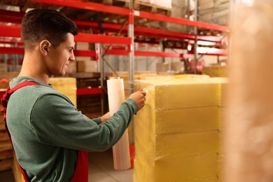 Photo of Worker wrapping boxes in stretch film at warehouse