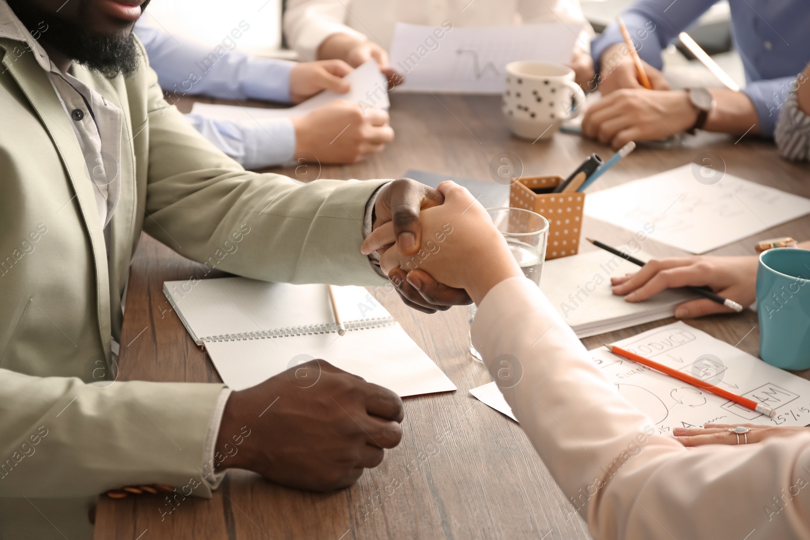 Photo of Man and woman shaking hands at table. Unity concept