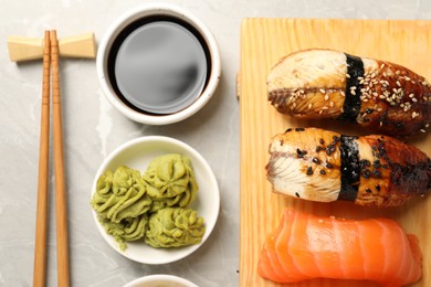 Photo of Delicious nigiri sushi, soy sauce, wasabi, ginger and chopsticks on light grey marble table, flat lay