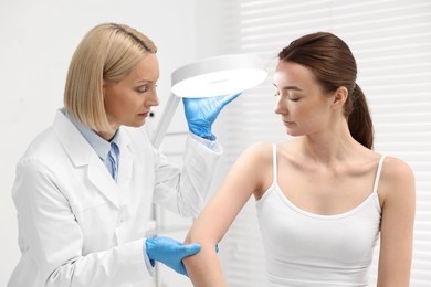 Dermatologist examining patient under lamp in clinic