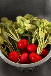 Photo of Fresh wet radishes in metal colander inside sink, closeup