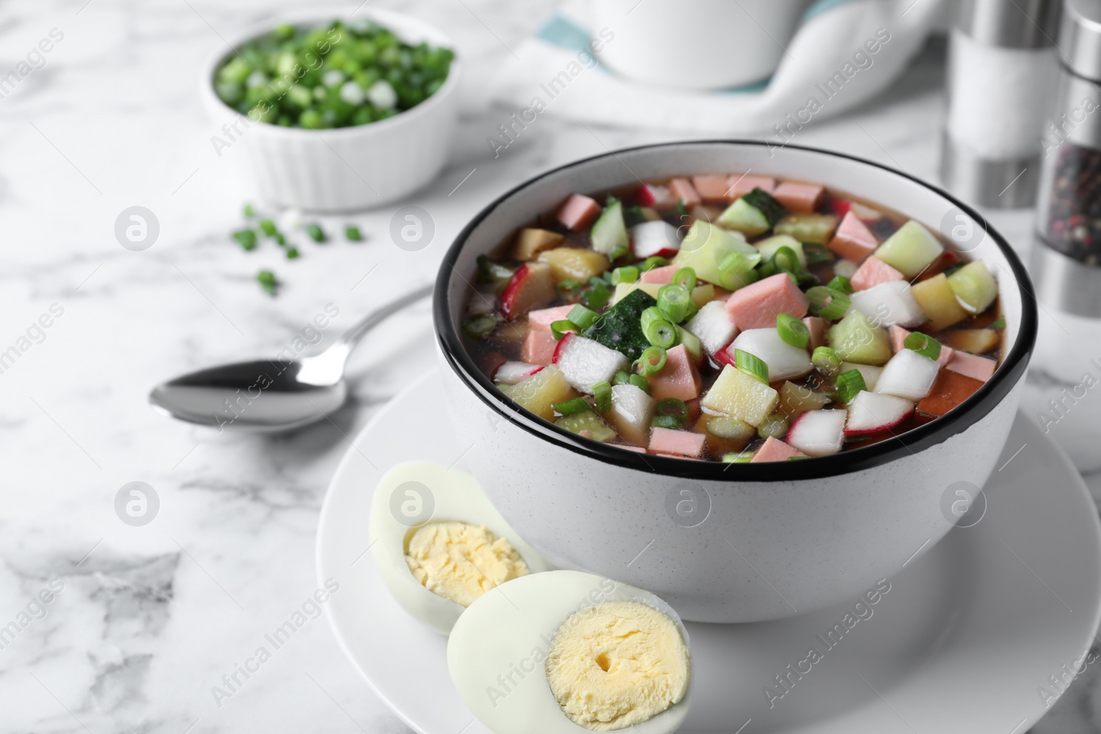 Photo of Delicious cold okroshka with kvass served on white marble table. Traditional Russian summer soup