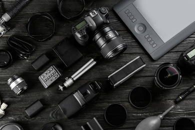 Flat lay composition with equipment for professional photographer on black wooden table