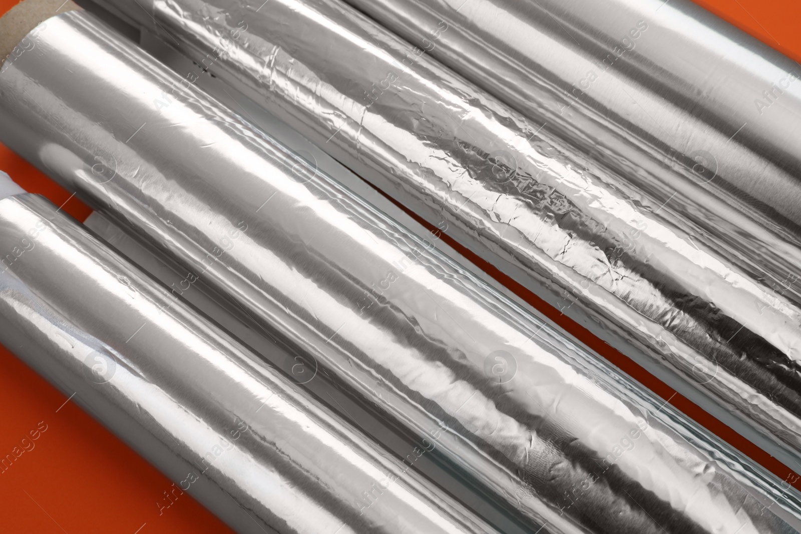 Photo of Rolls of aluminum foil on red background, closeup