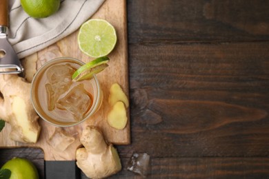 Photo of Glass of tasty ginger ale with ice cubes and ingredients on wooden table, flat lay. Space for text