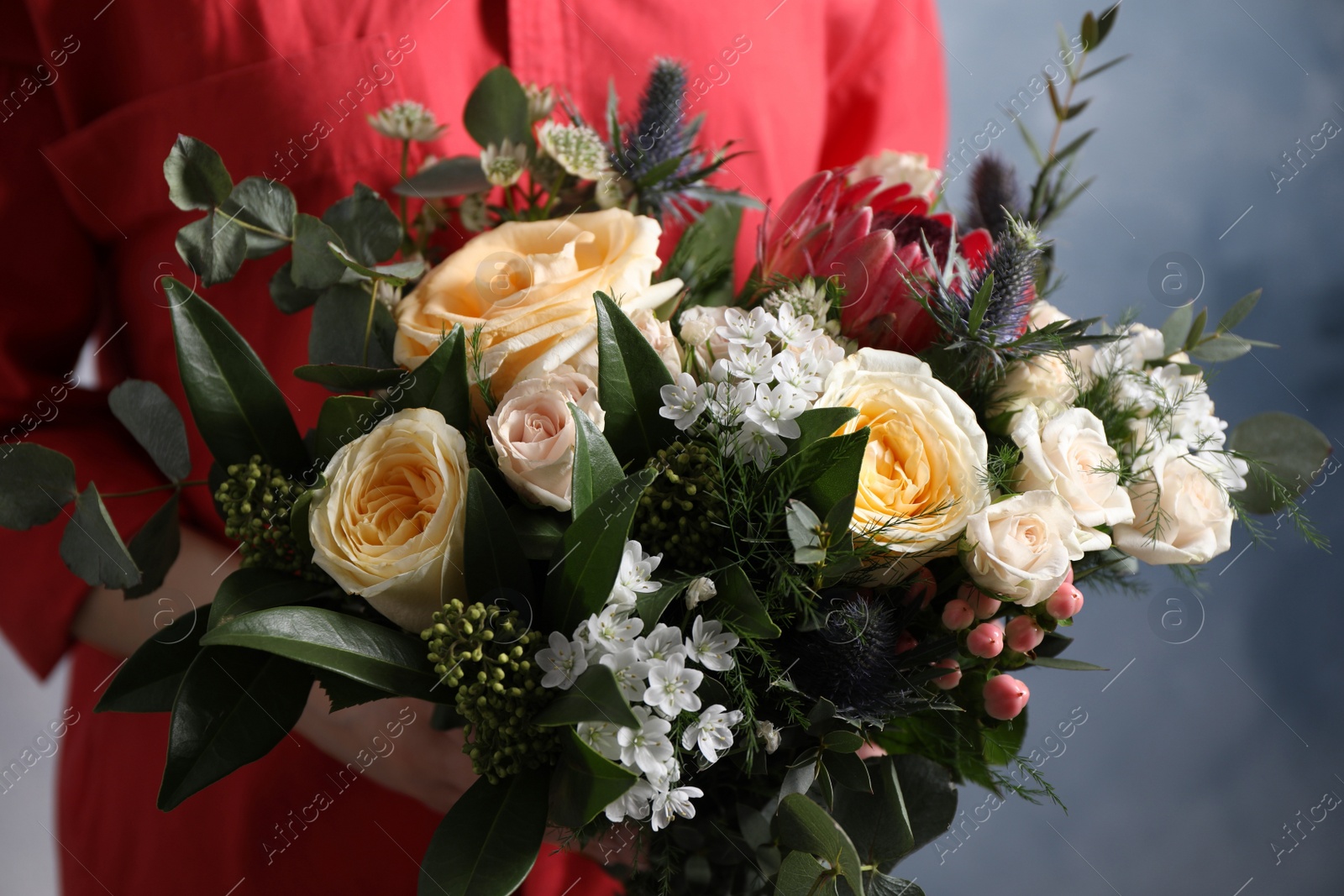 Photo of Woman with bouquet of beautiful roses on light blue background, closeup