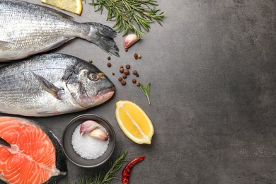 Flat lay composition with fresh raw dorado fish, salmon and spices on grey table. Space for text