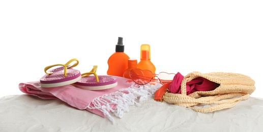 Different beach accessories on sand against white background