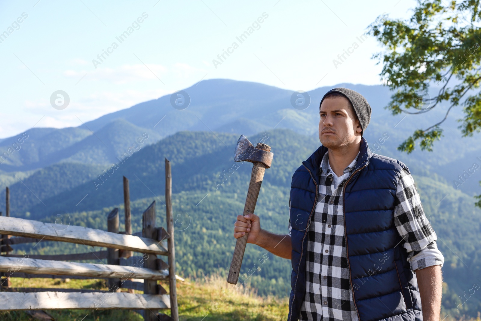 Photo of Handsome man with axe in mountains, space for text