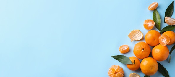 Image of Flat lay composition with fresh ripe tangerines and leaves on light blue background, space for text. Banner design