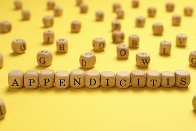 Photo of Word Appendicitis made of wooden cubes with letters on yellow background