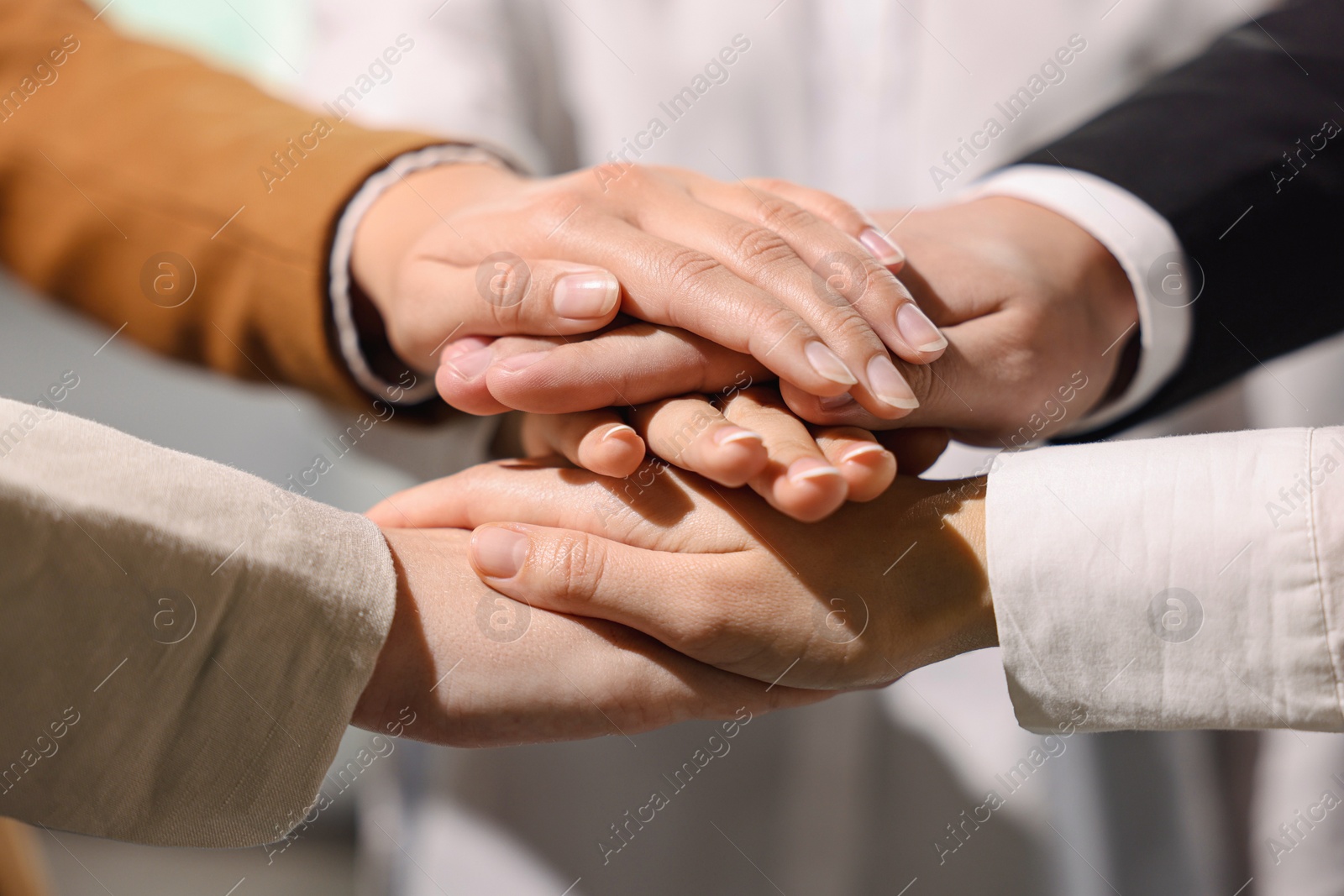 Photo of Group of people holding hands together indoors, closeup. Unity concept