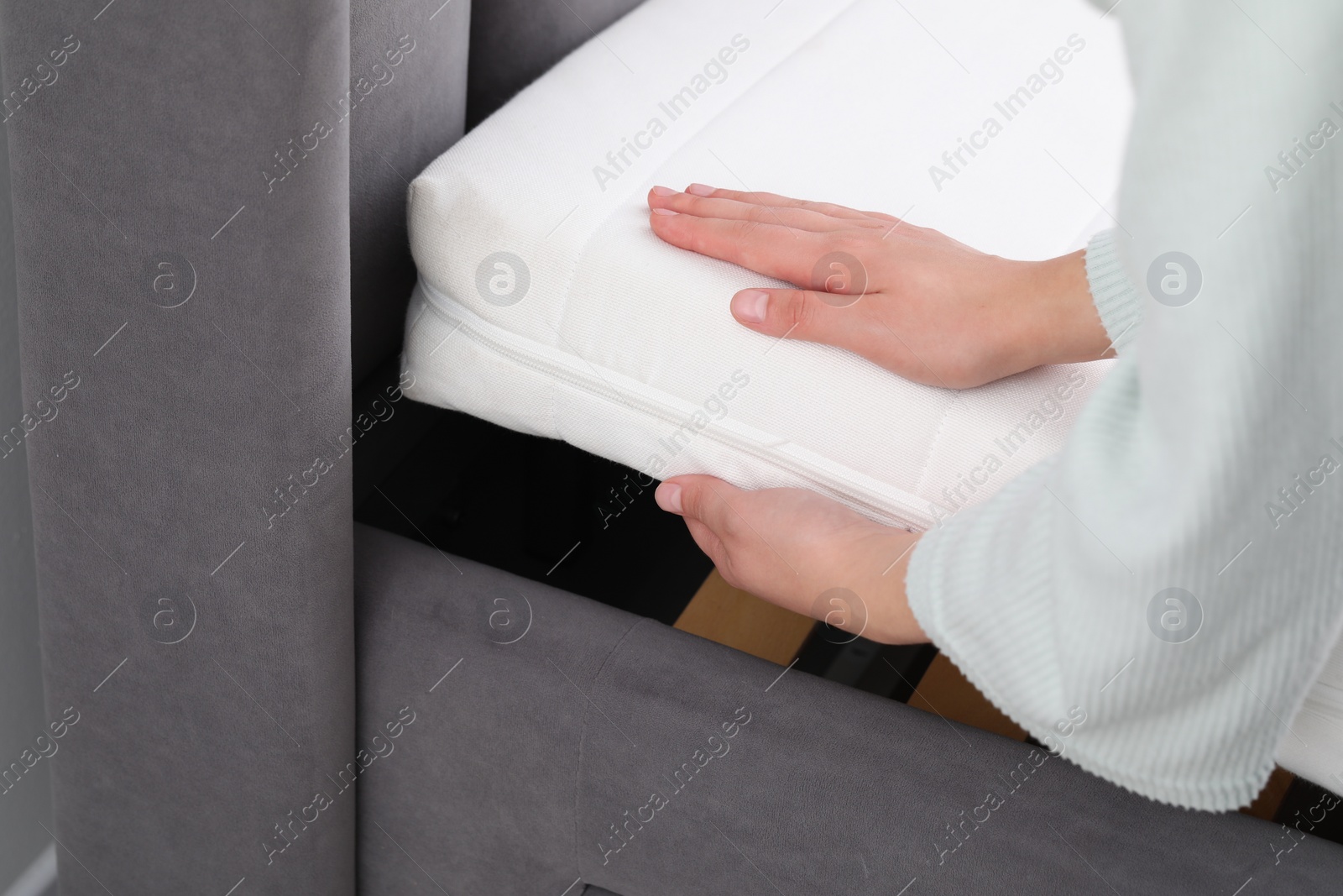 Photo of Woman putting new soft mattress on bed, closeup